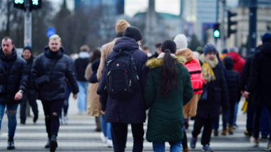 Varşova, Polonya. 29 Aralık 2023. Kalabalık kalabalık trafiğin en yoğun olduğu saatte trafik ışığı zebrasıyla karşıdan karşıya geçiyor. Europa 'da büyük bir şehirde yaşam tarzı.