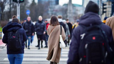 Varşova, Polonya. 29 Aralık 2023. Kalabalık kalabalık trafiğin en yoğun olduğu saatte trafik ışığı zebrasıyla karşıdan karşıya geçiyor. Europa 'da büyük bir şehirde yaşam tarzı.
