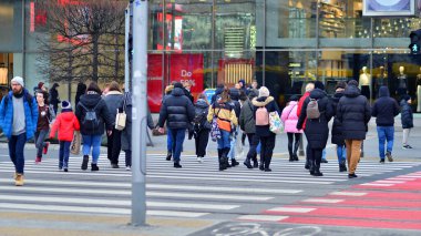 Varşova, Polonya. 29 Aralık 2023. Kalabalık kalabalık trafiğin en yoğun olduğu saatte trafik ışığı zebrasıyla karşıdan karşıya geçiyor. Europa 'da büyük bir şehirde yaşam tarzı.