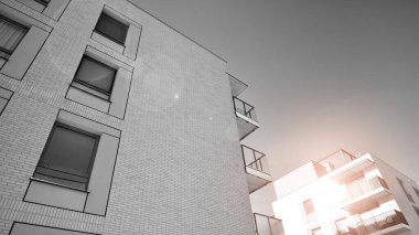 Pencereleri ve balkonları olan bir binanın ön cephesi. Güneşli bir günde modern apartman binaları. Modern bir apartmanın ön cephesi. Siyah ve beyaz.