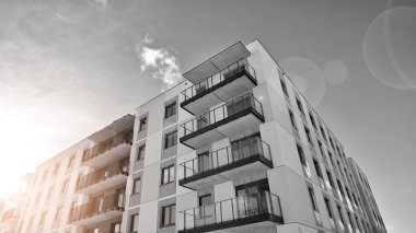 Pencereleri ve balkonları olan bir binanın ön cephesi. Güneşli bir günde modern apartman binaları. Modern bir apartmanın ön cephesi. Siyah ve beyaz.