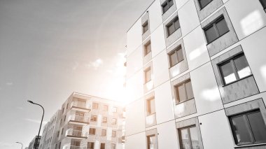 Pencereleri ve balkonları olan bir binanın ön cephesi. Güneşli bir günde modern apartman binaları. Modern bir apartmanın ön cephesi. Siyah ve beyaz.