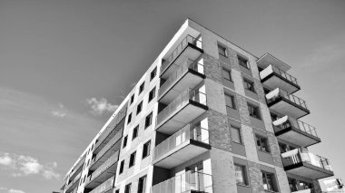 Pencereleri ve balkonları olan bir binanın ön cephesi. Güneşli bir günde modern apartman binaları. Modern bir apartmanın ön cephesi. Siyah ve beyaz.