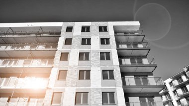 Pencereleri ve balkonları olan bir binanın ön cephesi. Güneşli bir günde modern apartman binaları. Modern bir apartmanın ön cephesi. Siyah ve beyaz.