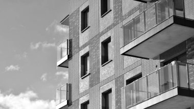Pencereleri ve balkonları olan bir binanın ön cephesi. Güneşli bir günde modern apartman binaları. Modern bir apartmanın ön cephesi. Siyah ve beyaz.