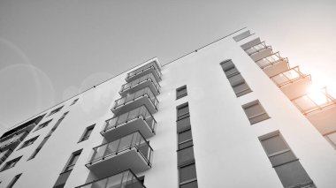 Pencereleri ve balkonları olan bir binanın ön cephesi. Güneşli bir günde modern apartman binaları. Modern bir apartmanın ön cephesi. Siyah ve beyaz.