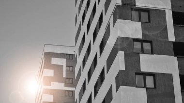 Pencereleri ve balkonları olan bir binanın ön cephesi. Güneşli bir günde modern apartman binaları. Modern bir apartmanın ön cephesi. Siyah ve beyaz.
