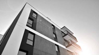 Pencereleri ve balkonları olan bir binanın ön cephesi. Güneşli bir günde modern apartman binaları. Modern bir apartmanın ön cephesi. Siyah ve beyaz.