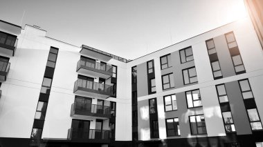 Pencereleri ve balkonları olan bir binanın ön cephesi. Güneşli bir günde modern apartman binaları. Modern bir apartmanın ön cephesi. Siyah ve beyaz.