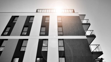 Pencereleri ve balkonları olan bir binanın ön cephesi. Güneşli bir günde modern apartman binaları. Modern bir apartmanın ön cephesi. Siyah ve beyaz.