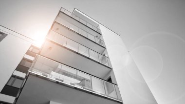 Pencereleri ve balkonları olan bir binanın ön cephesi. Güneşli bir günde modern apartman binaları. Modern bir apartmanın ön cephesi. Siyah ve beyaz.