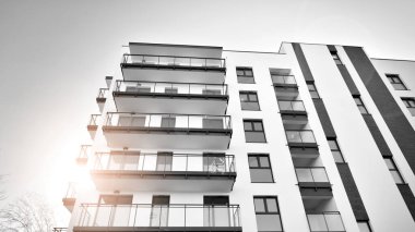 Pencereleri ve balkonları olan bir binanın ön cephesi. Güneşli bir günde modern apartman binaları. Modern bir apartmanın ön cephesi. Siyah ve beyaz.