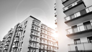 Pencereleri ve balkonları olan bir binanın ön cephesi. Güneşli bir günde modern apartman binaları. Modern bir apartmanın ön cephesi. Siyah ve beyaz.
