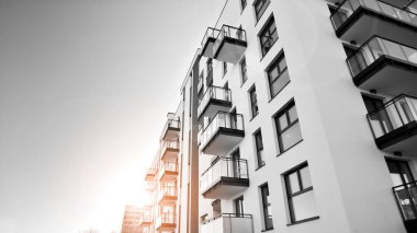 Pencereleri ve balkonları olan bir binanın ön cephesi. Güneşli bir günde modern apartman binaları. Modern bir apartmanın ön cephesi. Siyah ve beyaz.