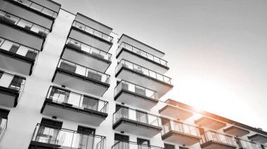 Pencereleri ve balkonları olan bir binanın ön cephesi. Güneşli bir günde modern apartman binaları. Modern bir apartmanın ön cephesi. Siyah ve beyaz.
