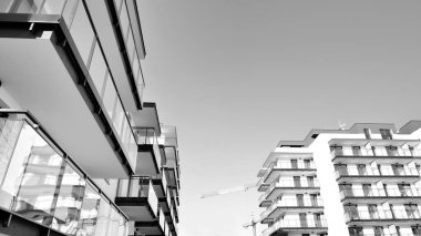 Pencereleri ve balkonları olan bir binanın ön cephesi. Güneşli bir günde modern apartman binaları. Modern bir apartmanın ön cephesi. Siyah ve beyaz.