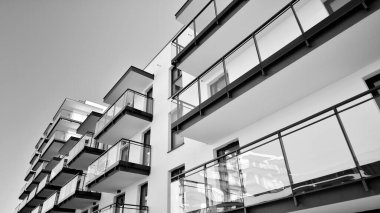 Pencereleri ve balkonları olan bir binanın ön cephesi. Güneşli bir günde modern apartman binaları. Modern bir apartmanın ön cephesi. Siyah ve beyaz.