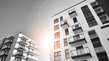 Pencereleri ve balkonları olan bir binanın ön cephesi. Güneşli bir günde modern apartman binaları. Modern bir apartmanın ön cephesi. Siyah ve beyaz.