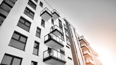 Pencereleri ve balkonları olan bir binanın ön cephesi. Güneşli bir günde modern apartman binaları. Modern bir apartmanın ön cephesi. Siyah ve beyaz.