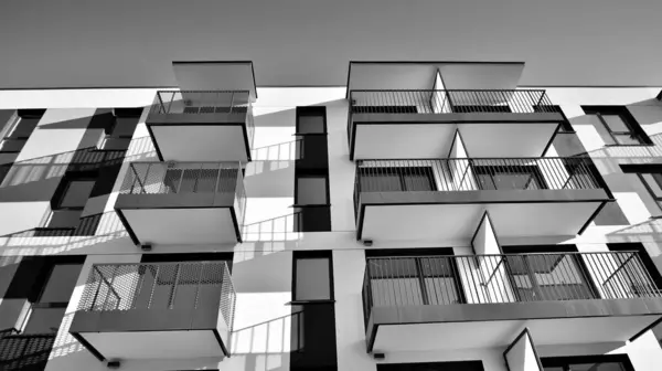 Fragment of a facade of a building with windows and balconies. Modern apartment buildings on a sunny day. Facade of a modern apartment building. Black and white.