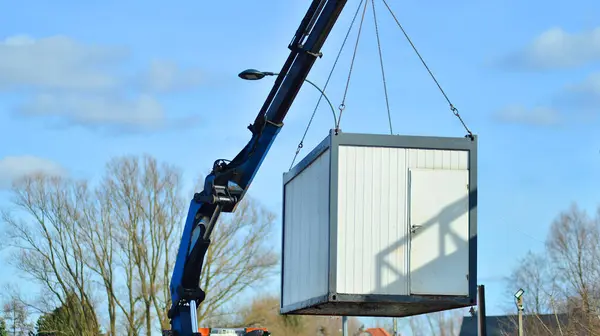 A crane transports a housing container to the construction site.
