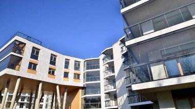 Eşsiz bir mimari çözümü olan bir apartman. Beyaz cepheli ve yüksek beton sütunların üzerinde duran modern bir yerleşim yeri..