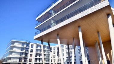 Eşsiz bir mimari çözümü olan bir apartman. Beyaz cepheli ve yüksek beton sütunların üzerinde duran modern bir yerleşim yeri..