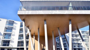 Eşsiz bir mimari çözümü olan bir apartman. Beyaz cepheli ve yüksek beton sütunların üzerinde duran modern bir yerleşim yeri..