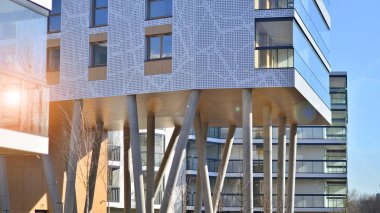 Eşsiz bir mimari çözümü olan bir apartman. Beyaz cepheli ve yüksek beton sütunların üzerinde duran modern bir yerleşim yeri..