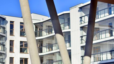 Eşsiz bir mimari çözümü olan bir apartman. Beyaz cepheli ve yüksek beton sütunların üzerinde duran modern bir yerleşim yeri..