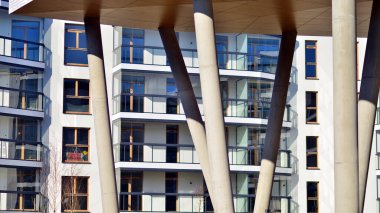 Eşsiz bir mimari çözümü olan bir apartman. Beyaz cepheli ve yüksek beton sütunların üzerinde duran modern bir yerleşim yeri..