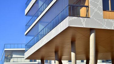 Eşsiz bir mimari çözümü olan bir apartman. Beyaz cepheli ve yüksek beton sütunların üzerinde duran modern bir yerleşim yeri..