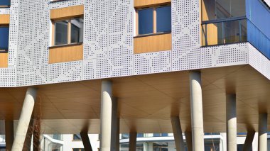 Eşsiz bir mimari çözümü olan bir apartman. Beyaz cepheli ve yüksek beton sütunların üzerinde duran modern bir yerleşim yeri..