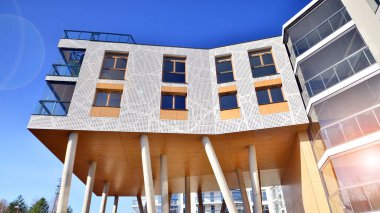 Eşsiz bir mimari çözümü olan bir apartman. Beyaz cepheli ve yüksek beton sütunların üzerinde duran modern bir yerleşim yeri..