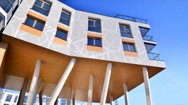 Eşsiz bir mimari çözümü olan bir apartman. Beyaz cepheli ve yüksek beton sütunların üzerinde duran modern bir yerleşim yeri..