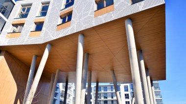 Eşsiz bir mimari çözümü olan bir apartman. Beyaz cepheli ve yüksek beton sütunların üzerinde duran modern bir yerleşim yeri..