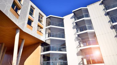 Eşsiz bir mimari çözümü olan bir apartman. Beyaz cepheli ve yüksek beton sütunların üzerinde duran modern bir yerleşim yeri..