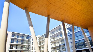 Eşsiz bir mimari çözümü olan bir apartman. Beyaz cepheli ve yüksek beton sütunların üzerinde duran modern bir yerleşim yeri..