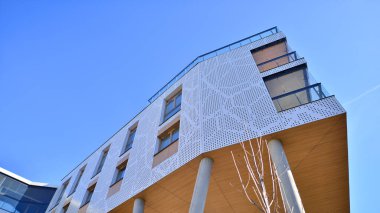 Eşsiz bir mimari çözümü olan bir apartman. Beyaz cepheli ve yüksek beton sütunların üzerinde duran modern bir yerleşim yeri..