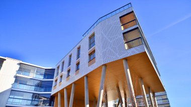 Eşsiz bir mimari çözümü olan bir apartman. Beyaz cepheli ve yüksek beton sütunların üzerinde duran modern bir yerleşim yeri..