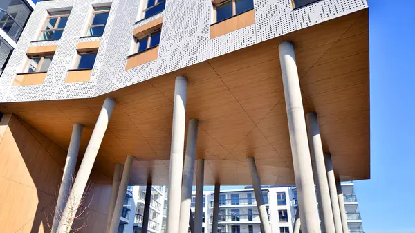 Eşsiz bir mimari çözümü olan bir apartman. Beyaz cepheli ve yüksek beton sütunların üzerinde duran modern bir yerleşim yeri..