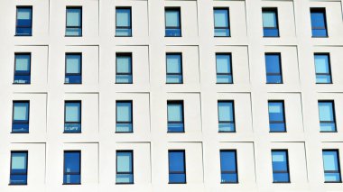 Beyaz, modern bir apartman manzarası. Mavi gökyüzü ile mükemmel bir simetri. Geometrik mimari modern beton yapı yapısını detaylandırıyor. Soyut somut mimari. 