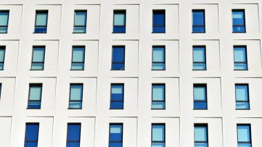 Beyaz, modern bir apartman manzarası. Mavi gökyüzü ile mükemmel bir simetri. Geometrik mimari modern beton yapı yapısını detaylandırıyor. Soyut somut mimari. 