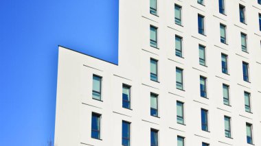 Beyaz, modern bir apartman manzarası. Mavi gökyüzü ile mükemmel bir simetri. Geometrik mimari modern beton yapı yapısını detaylandırıyor. Soyut somut mimari. 