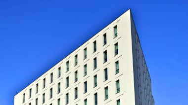 Beyaz, modern bir apartman manzarası. Mavi gökyüzü ile mükemmel bir simetri. Geometrik mimari modern beton yapı yapısını detaylandırıyor. Soyut somut mimari. 