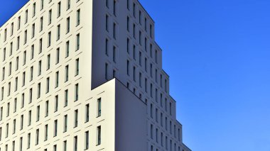 Beyaz, modern bir apartman manzarası. Mavi gökyüzü ile mükemmel bir simetri. Geometrik mimari modern beton yapı yapısını detaylandırıyor. Soyut somut mimari. 