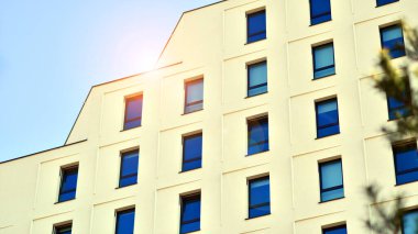 Beyaz, modern bir apartman manzarası. Mavi gökyüzü ile mükemmel bir simetri. Geometrik mimari modern beton yapı yapısını detaylandırıyor. Soyut somut mimari. 