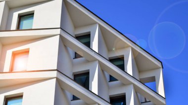 Beyaz, modern bir apartman manzarası. Mavi gökyüzü ile mükemmel bir simetri. Geometrik mimari modern beton yapı yapısını detaylandırıyor. Soyut somut mimari. 