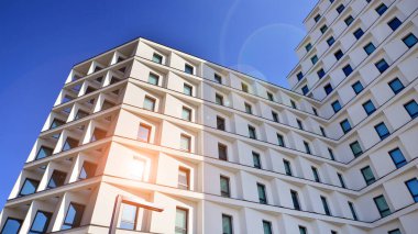 Beyaz, modern bir apartman manzarası. Mavi gökyüzü ile mükemmel bir simetri. Geometrik mimari modern beton yapı yapısını detaylandırıyor. Soyut somut mimari. 