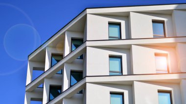 Beyaz, modern bir apartman manzarası. Mavi gökyüzü ile mükemmel bir simetri. Geometrik mimari modern beton yapı yapısını detaylandırıyor. Soyut somut mimari. 